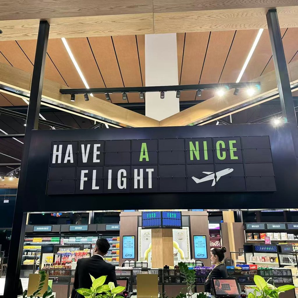 Custom split flap display installed in an airport restaurant, showing “Have a Nice Flight” with an airplane graphic.