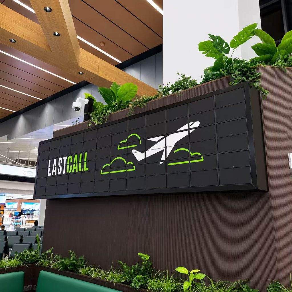 Custom picture flap display installed in an airport restaurant, showing the Last Call logo with airplane graphics and green travel-themed visuals.