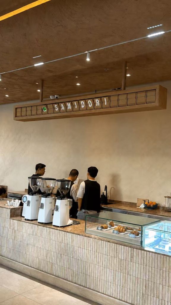 Oak-tone split flap display showing the SANDORI brand name above the counter in a cafe in Davao, Philippines