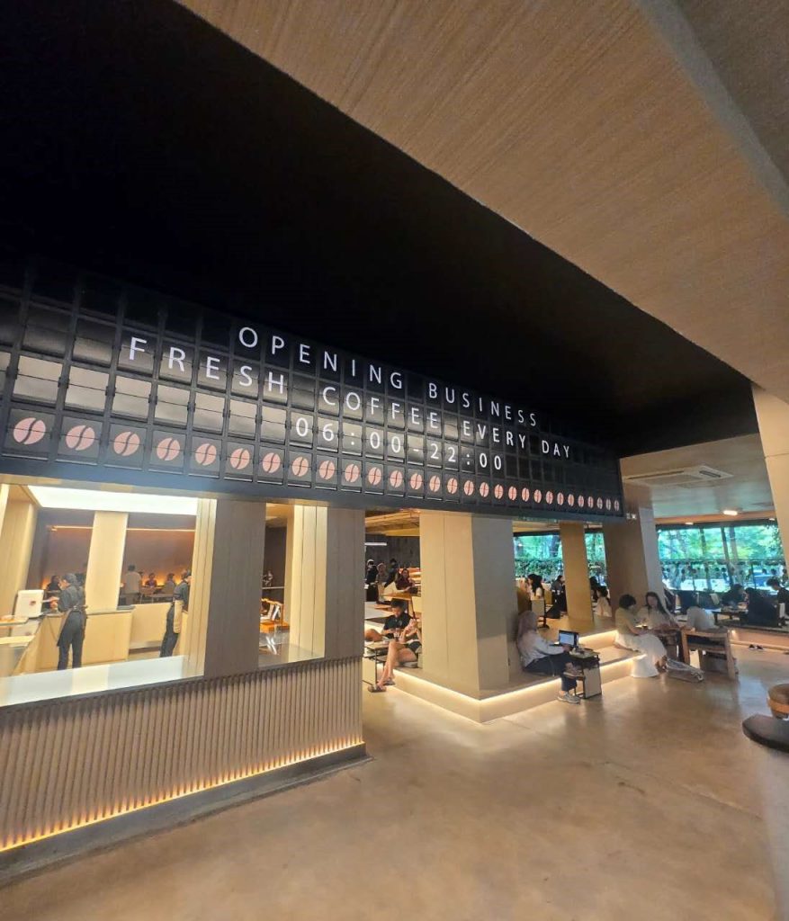 Mechanical split flap board displaying café opening hours and coffee graphics