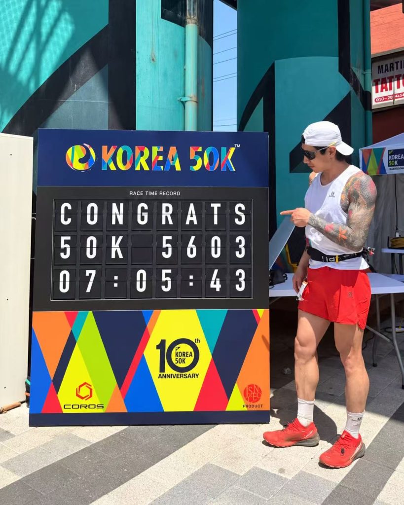 KOREA 50K runner pointing at his finishing result on a TS Display split flap race time board.